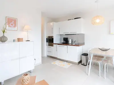 a white kitchen with white cabinets and a table at Pavillon lumineux avec terrasse, à 1 km de la plage – 2 pièces, 1 chambre, barbecue, Wi-Fi - FR-1-409A-3 in Gruissan