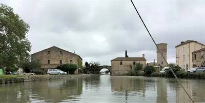 a river with cars parked next to some buildings at Gite de charme à 10 min de Narbonne in Moussan