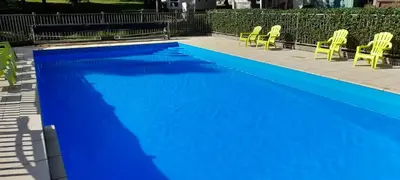 a blue swimming pool with yellow chairs next to it at Cabane randonneur au camping in Camurac