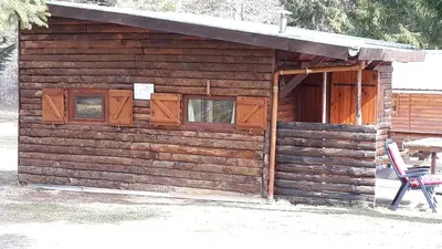 a wooden cabin with a chair in front of it at Cabane randonneur au camping in Camurac