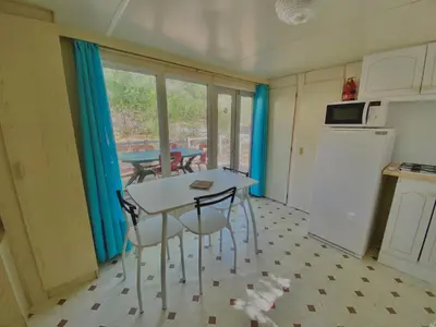 a kitchen with a table and two chairs and a table at Camping Caramany, Lac à proximité - Cabanes perchées - Mobil-homes - Emplacements nus pour camping-cars, tentes, caravanes in Caramany