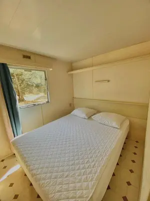 a bed in a small room with a window at Camping Caramany, Lac à proximité - Cabanes perchées - Mobil-homes - Emplacements nus pour camping-cars, tentes, caravanes in Caramany
