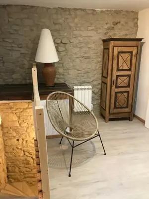 a chair in a room with a table and a lamp at Le grenier de Manée in Villemoustaussou