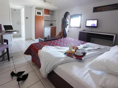 a woman standing next to a bed in a room at res La Barbacane, Carcassonne, studio for 2 people in Carcassonne