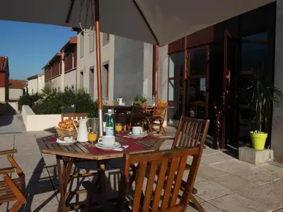 a wooden table with chairs and an umbrella on a patio at res La Barbacane, Carcassonne, studio for 2 people in Carcassonne