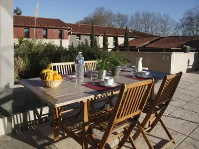 a wooden table with a basket of fruit on a patio at Res La Barbacane, Carcassonne, apartment for 4 pers in Carcassonne