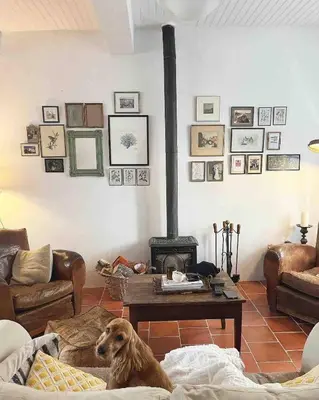 a dog sitting on a couch in a living room with a fireplace at La Maison de Mama C: Charming french village home in Sainte-Colombe-sur-lʼHers