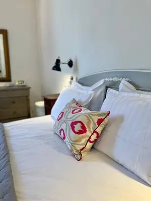 a bed with white sheets and a pillow on it at La Maison de Mama C: Charming french village home in Sainte-Colombe-sur-lʼHers