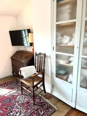 a room with a chair and a cabinet and a television at La Maison de Mama C: Charming french village home in Sainte-Colombe-sur-lʼHers
