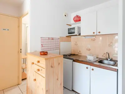 a small kitchen with white cabinets and a sink at Appartement à Gruissan avec Piscine - 4 Pers. - FR-1-409A-8 in Narbonne