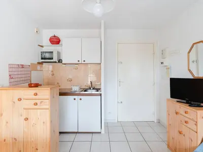 a small kitchen with white cabinets and a television at Appartement à Gruissan avec Piscine - 4 Pers. - FR-1-409A-8 in Narbonne