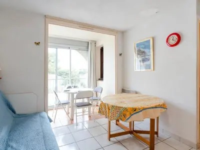 a room with a table and a dining room with a window at Appartement à Gruissan avec Piscine - 4 Pers. - FR-1-409A-8 in Narbonne