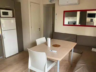 a kitchen and dining room with a table and a couch at Mobilhome « Candice » in Sigean