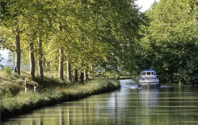 a boat traveling down a river with trees at 1 Bedroom Gorgeous Home In Capestang in Capestang
