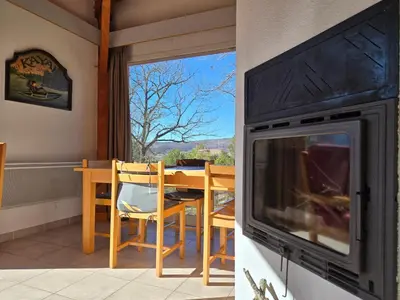 a living room with a fireplace and a table with chairs at Evasion en pays Cathare in Quillan