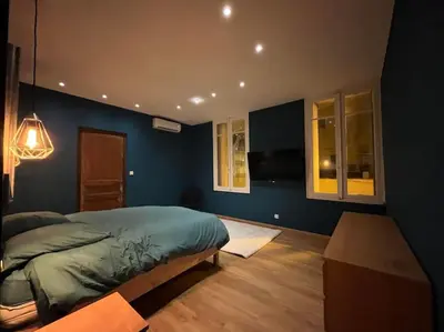 a bedroom with blue walls and a bed and a table at Appartement Haussmannien a 200m des Halles. in Narbonne