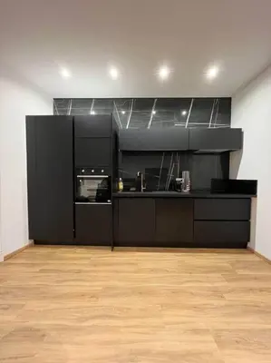 a kitchen with black cabinets and a wooden floor at Appartement Haussmannien a 200m des Halles. in Narbonne