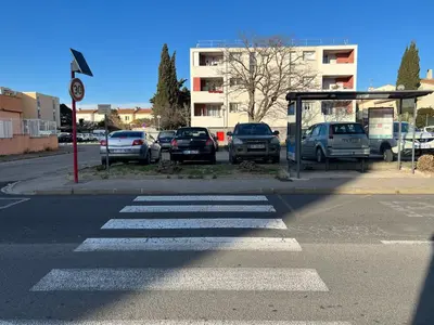 a bus stop with cars parked in a parking lot at A Narbonne studio quartier Horte neuve in Narbonne