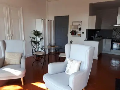 a living room with two chairs and a table at Appartement avec balcon, bord du canal, Wifi. in Narbonne