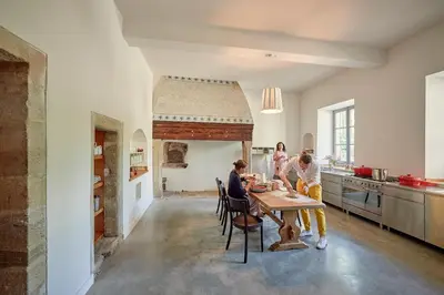 a group of people sitting at a table in a kitchen at Château de Sibra in Lagarde