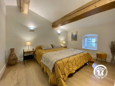 a bedroom with a large bed and a wooden floor at Le mas de l'ecluse in Caux-et-Sauzens