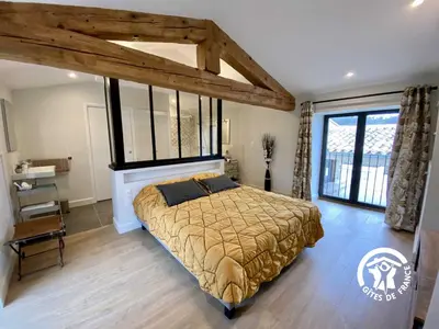 a bedroom with a bed and a large window at Le mas de l'ecluse in Caux-et-Sauzens