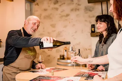 a man pouring a glass of wine at a table at Le mas de l'ecluse in Caux-et-Sauzens