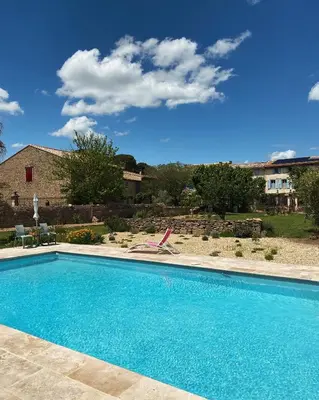 a large blue swimming pool in front of a house at Gîte - Le Relais d'Affiac in Peyriac-Minervois