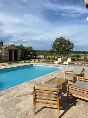 a swimming pool with two chairs and a wooden table next to it at Gîte - Le Relais d'Affiac in Peyriac-Minervois