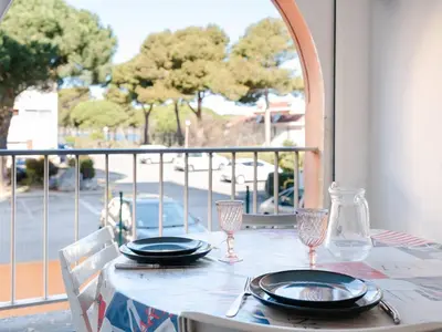 a table with plates and wine glasses on a balcony at T2 avec Piscine à Gruissan - Proche Plage et Commerces - FR-1-409A-14 in Gruissan