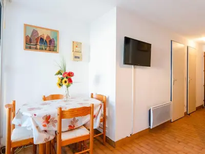 a dining room with a table and chairs and a television at T2 avec Piscine à Gruissan - Proche Plage et Commerces - FR-1-409A-14 in Gruissan