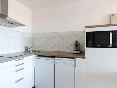 a kitchen with white cabinets and a microwave at Appartement Gruissan - Parking Privé, Animaux Acceptés - FR-1-409A-16 in Gruissan