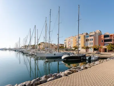 a row of boats docked in a harbor with buildings at Appartement Gruissan - Parking Privé, Animaux Acceptés - FR-1-409A-16 in Gruissan