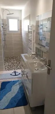 a bathroom with a white sink and a blue rug at Chez Reinette in Capendu