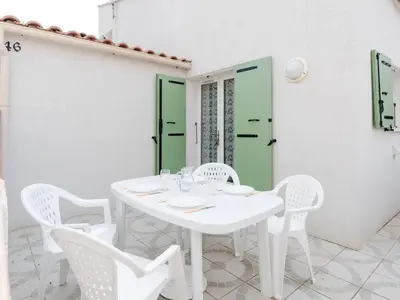 a white table with white chairs and a green door at Chaleureuse Villa à Gruissan - 6 pers, Près de la Plage, Garage, Cuisine Équipée, Confort Moderne - FR-1-409A-17 in Gruissan