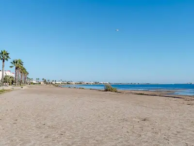 a sandy beach with palm trees and the ocean at Chaleureuse Villa à Gruissan - 6 pers, Près de la Plage, Garage, Cuisine Équipée, Confort Moderne - FR-1-409A-17 in Gruissan