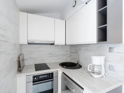 a white kitchen with white cabinets and a blender at Chaleureuse Villa à Gruissan - 6 pers, Près de la Plage, Garage, Cuisine Équipée, Confort Moderne - FR-1-409A-17 in Gruissan
