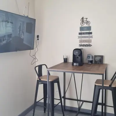 a table with two chairs and a tv on a wall at Chambre avec piscine partagée in Marcorignan
