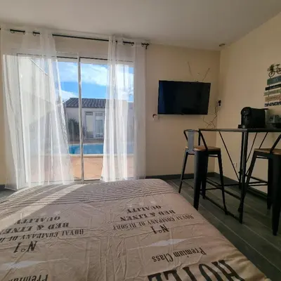 a bedroom with a bed and a television and a window at Chambre avec piscine partagée in Marcorignan