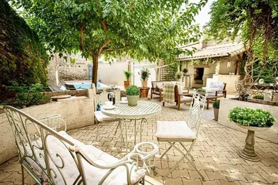 a patio with white chairs and a table and a table at La Chasse au Bonheur Piscine-Wifi in Rieux-Minervois