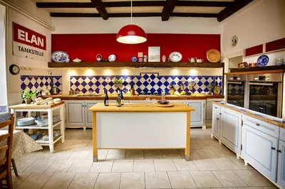 a kitchen with white cabinets and a red wall at La Chasse au Bonheur Piscine-Wifi in Rieux-Minervois