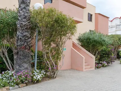 a palm tree in front of a building with flowers at Duplex lumineux à Gruissan avec parking, proche plage et port - FR-1-409A-11 in Gruissan