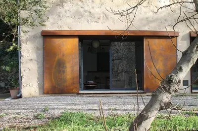 a building with an orange door and a window at L'écurie de Gamin - gîte 4 pers. dans le Minervois in Aigues-Vives