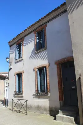 a white building with a black door and windows at La Cité Secrète in Carcassonne