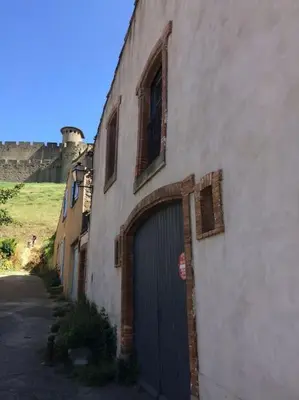 a building with a door and a castle in the background at La Cité Secrète in Carcassonne