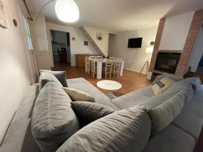 a living room with a gray couch and a living room with a table at Lauraguel Gîte in Mourvilles-Hautes