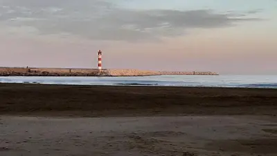 a lighthouse sitting on the shore of a beach at Agréable Studio en bord de mer in Port-la-Nouvelle