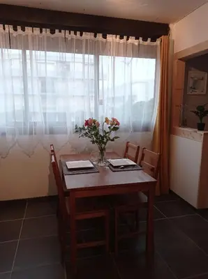 a dining room table with a vase of flowers on it at Agréable Studio en bord de mer in Port-la-Nouvelle