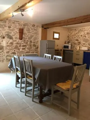 a table and chairs in a kitchen with a stone wall at Gîte Le Ribet in Lempaut