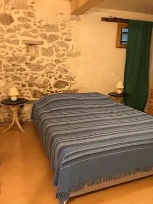 a bed in a room with a stone wall at Gîte Le Ribet in Lempaut